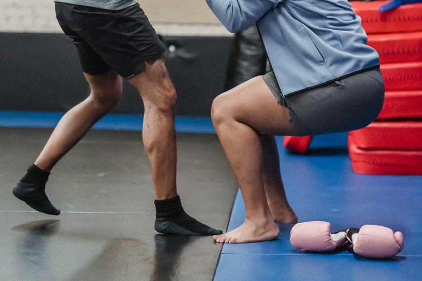 black trainer helping sportswoman to get up